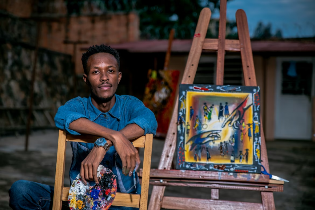 Picture of an artist sitting beside a canvas resting on an easel 